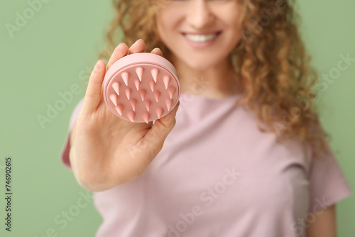 Foto Young woman with hair scalp massager on green background