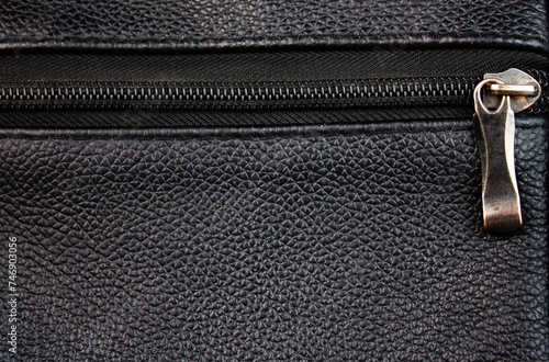 Metal clasp and zipper on the pocket of a leather purse or bag.