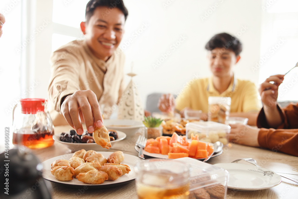 Young man taking cookies from the plate when iftar in Ramadan. Breakfasting concept