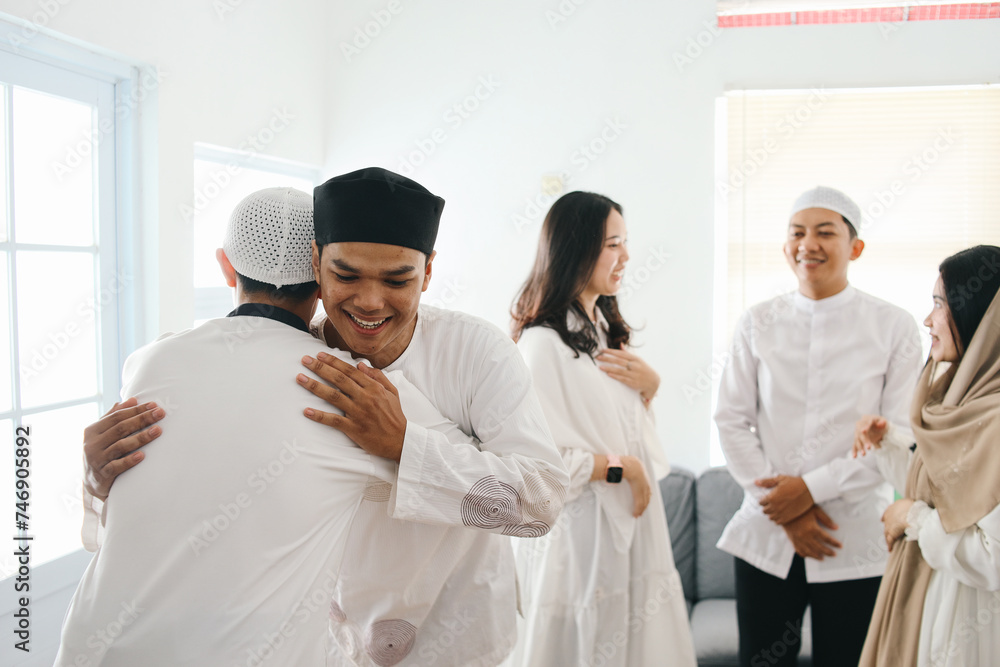 Young muslim men wear skullcap, hugging and smiling during Eid mubarak celebration. Islamic culture and tradition concept