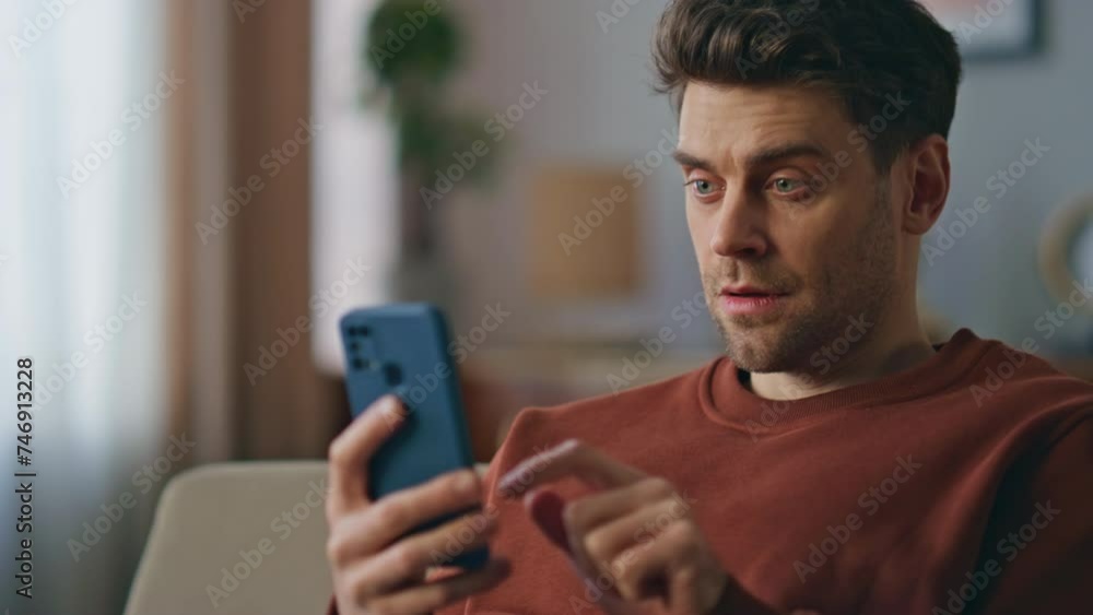 Closeup guy swiping cellphone choosing online purchase at home couch. Calm man Closeup guy swiping cellphone choosing online purchase at home couch. Calm man