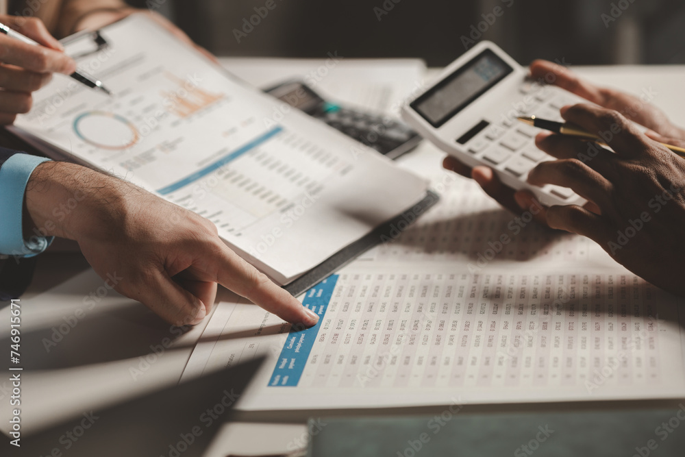 A group of three businesspeople are working together to calculate the company's numbers, employees are meeting about an important document that has many numbers that must be carefully calculated. A group of three businesspeople are working together to calculate the company's numbers, employees are meeting about an important document that has many numbers that must be carefully calculated.