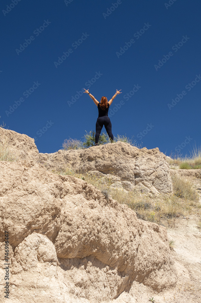 A person stands victorious atop a rugged summit, arms wide in jubilation against a clear blue sky, perfect for themes of success, freedom, and adventure. A person stands victorious atop a rugged summit, arms wide in jubilation against a clear blue sky, perfect for themes of success, freedom, and adventure.
