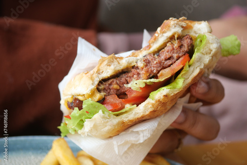 hand holding beef burger on table close up 