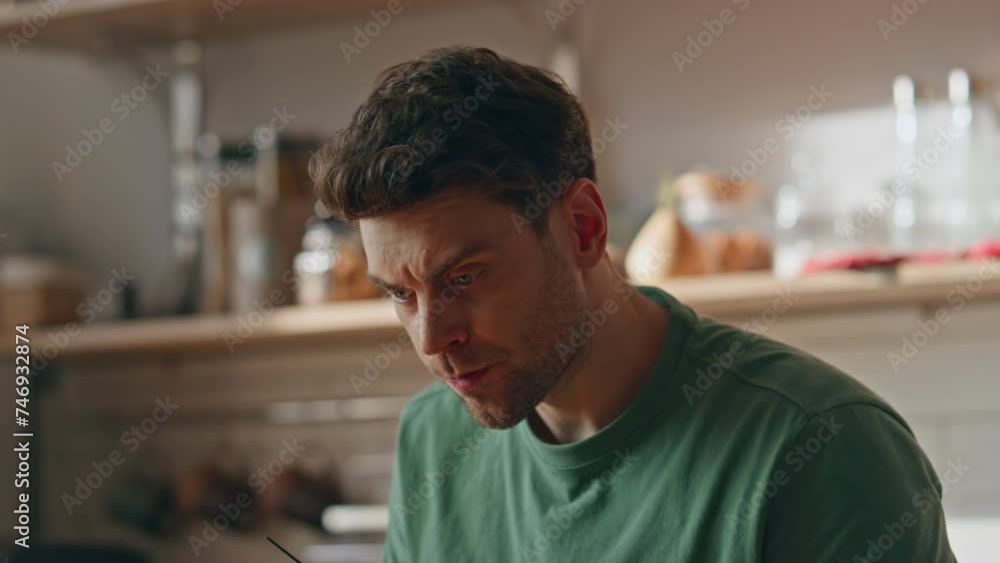 Unsmiled businessman eating breakfast at home closeup. Serious guy typing laptop Unsmiled businessman eating breakfast at home closeup. Serious guy typing laptop