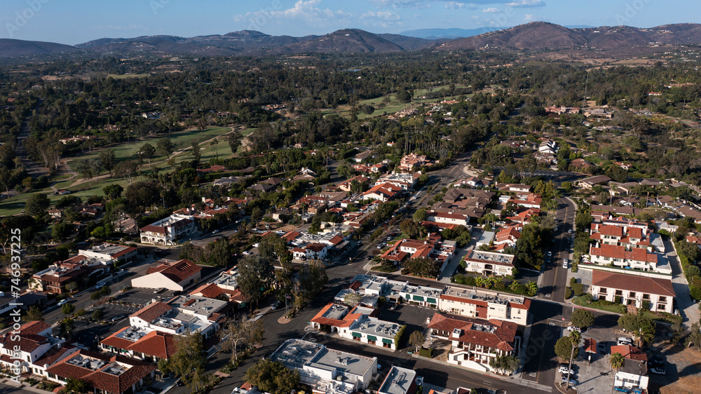 Fototapeta premium Afternoon aerial view of tree framed mission revival style architecture of historic downtown Rancho Santa Fe, California, USA.