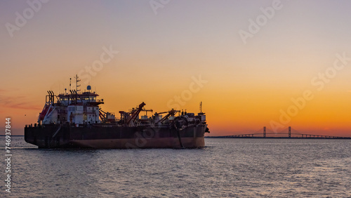 cargo ship sailing in to dock with a suspension bridge off in the distance in St. Simons, GA