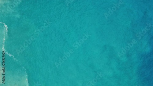 Drone descends on green clear ocean water churned with sand suspended, smooth texture photo