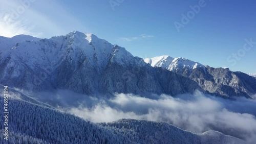 Majestic Bucegi Mountains with Bucsoiu Peak covered in snow under blue sky photo