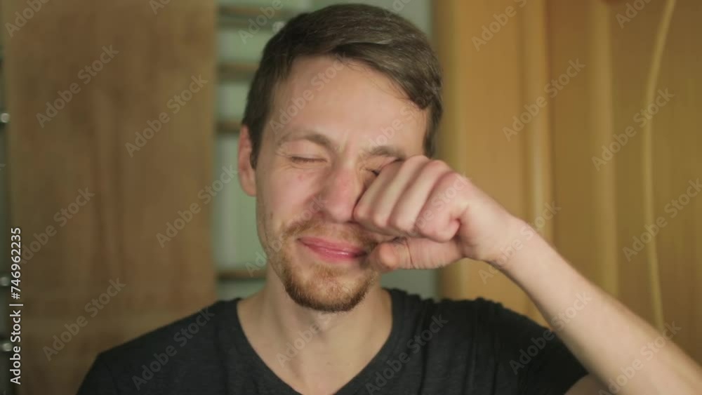 The young man looks at himself in the bathroom mirror and yawning, waking up. The young man looks at himself in the bathroom mirror and yawning, waking up.