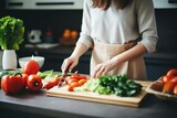 A woman in the kitchen preparing tomatoes and lettuce on a cutting board