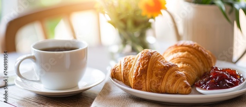 A dish of croissants with jam and a coffee cup on a saucer placed on the table.