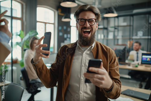 the moment of pure joy as a young businessman receives good news on his smartphone, celebrating a win with a cheerful yes gesture in the workplace.