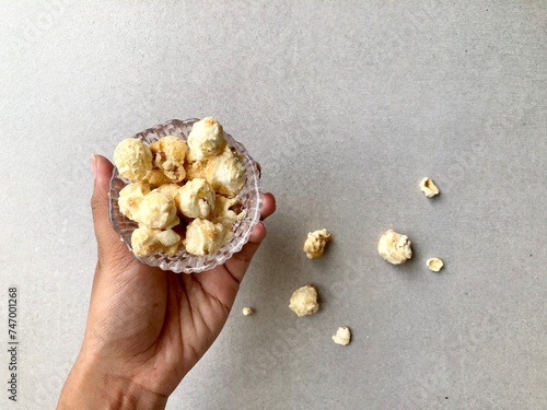 Hand holding bowl of popcorn on gray plain background photo