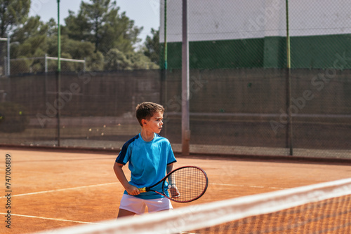 Little boy playing tennis on a dirt court © PEDROMERINO