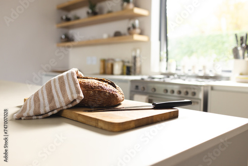 Freshly baked bread rests on a wooden cutting board in a bright kitchen, with copy space