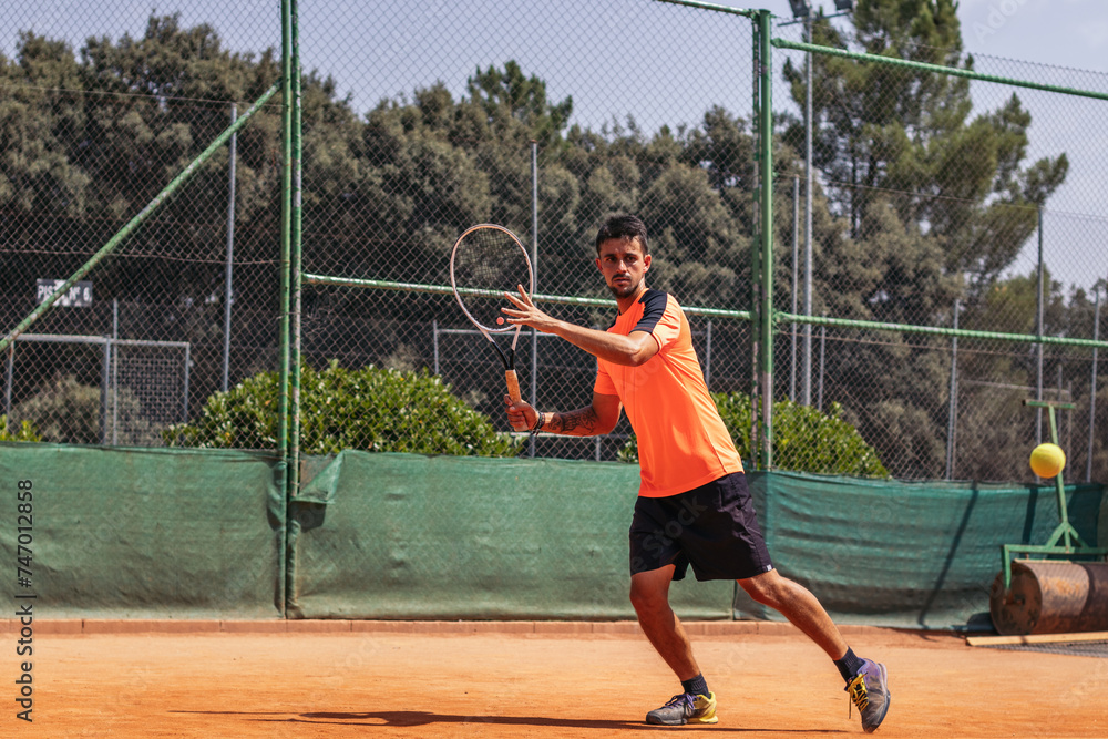 Man in sportswear playing tennis on a dirt tennis court