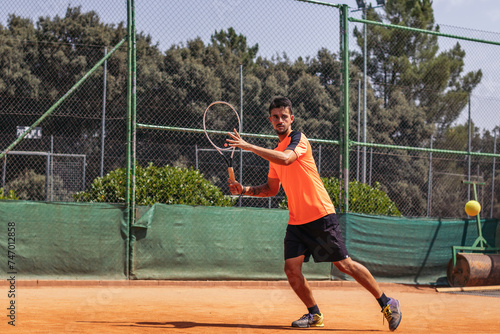 Man in sportswear playing tennis on a dirt tennis court © PEDROMERINO