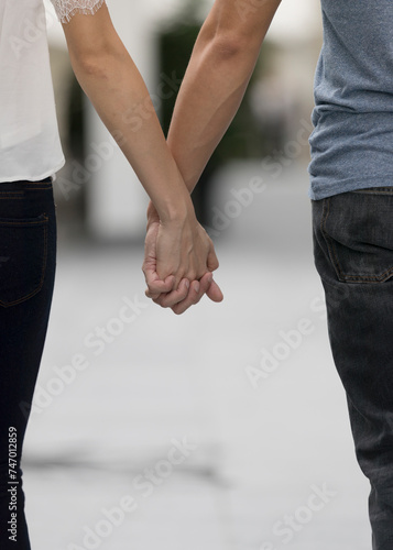 Close up of a man and woman holding hands.