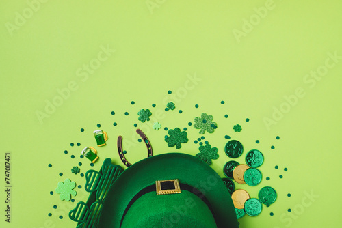Saint Patrick Day background with green decoration from shamrocks, leprechaun hat, golden coins and eyeglasses top view.