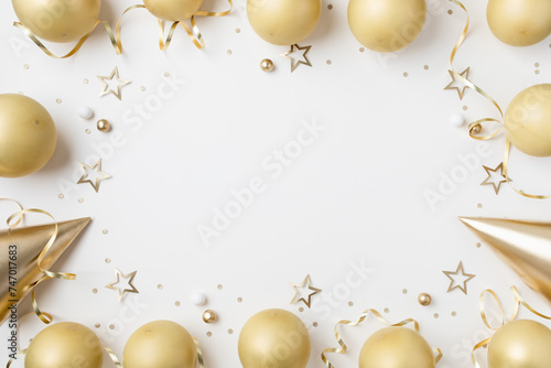 Stylish birthday party festive background with golden decoration from balloons, carnival cap and confetti stars on white table top view.
