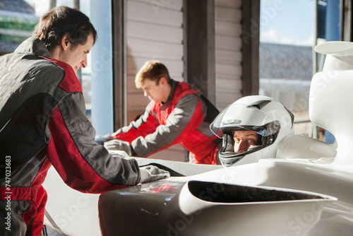 Racing team prepping the car with a focused driver in the cockpit. 