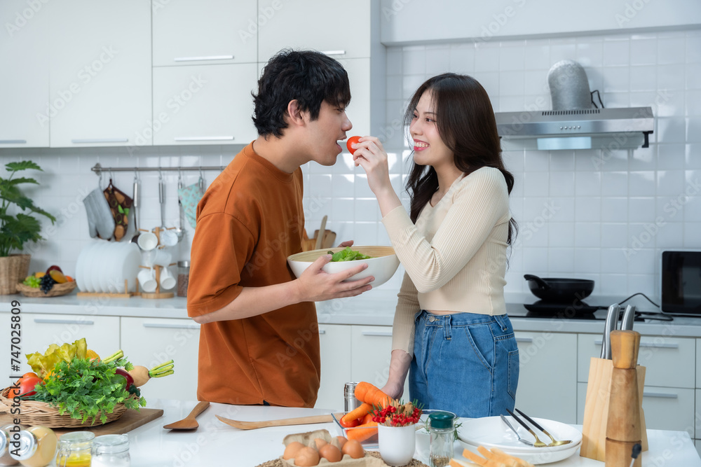 Happy portrait of loving young loving couple asian of having fun standing a cheerful preparing food and enjoy cook cooking with vegetables, meat, bread while standing on a kitchen Condo life or home