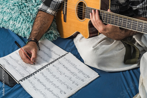 Colombian man reading sheet music and studying guitar. Acoustic and harmonic instrument