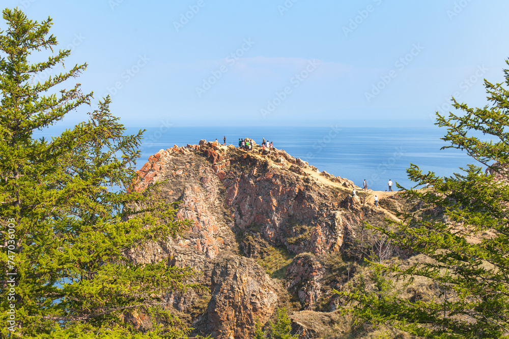 Baikal Lake on sunny summer day. Tourists climb to rocky Cape Shunte Left or as it is also called, Cape of Love on Olkhon Island and take pictures of beautiful landscape. Travel and outdoor activities Baikal Lake on sunny summer day. Tourists climb to rocky Cape Shunte Left or as it is also called, Cape of Love on Olkhon Island and take pictures of beautiful landscape. Travel and outdoor activities