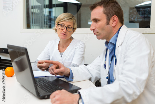 doctor and assistant looking at laptop