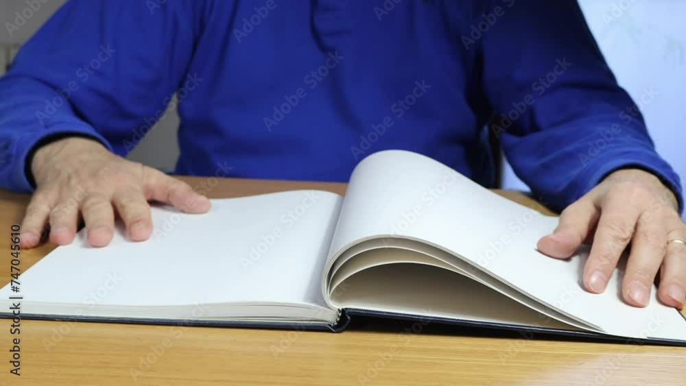 Hands rest on blank pages of diary, front view of senior man in blue t-shirt, copy space. Hands rest on blank pages of diary, front view of senior man in blue t-shirt, copy space.