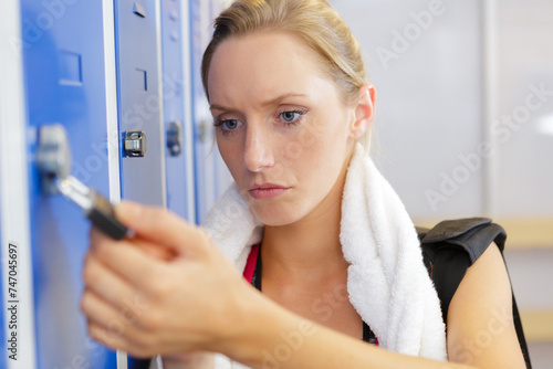 young woman opening a locker in a gym photo