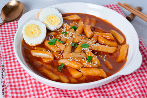 topokki or tteokbokki with two boiled eggs on a white plate and on a white background. perfect for recipes, articles, catalogues, commercials or any cooking content.