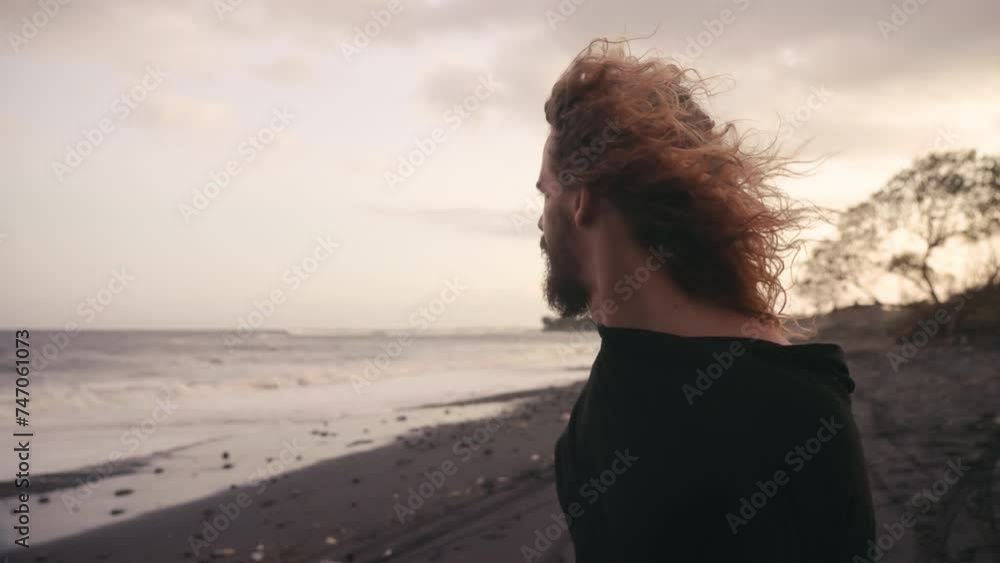 Dark cinematic slow motion view of lonely thoughtful man on seaside. Pensive mood. Adult male surfer feel blue on ocean shore. Solo traveler enjoying nature at warm color sunset. Live motion camera Dark cinematic slow motion view of lonely thoughtful man on seaside. Pensive mood. Adult male surfer feel blue on ocean shore. Solo traveler enjoying nature at warm color sunset. Live motion camera