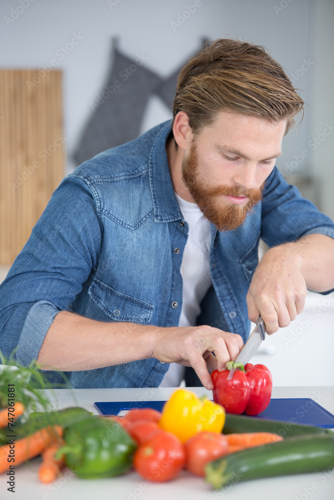 Fototapeta premium young man cutting vegetables