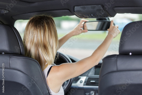 woman looking into rear view mirror while driving a car © auremar