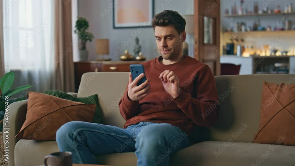 Serious customer looking cellphone making online order at home. Man swiping Serious customer looking cellphone making online order at home. Man swiping
