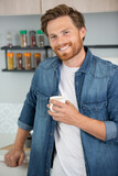 confident man at home holding a cup of coffee