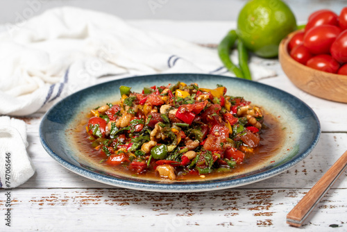 Salad with vegetables and walnuts. Traditional Asian flavors. Gavurdagi salad on white wood background. Close up