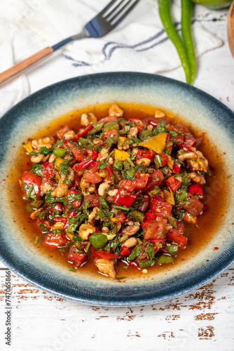 Salad with vegetables and walnuts. Traditional Asian flavors. Gavurdagi salad on white wood background photo