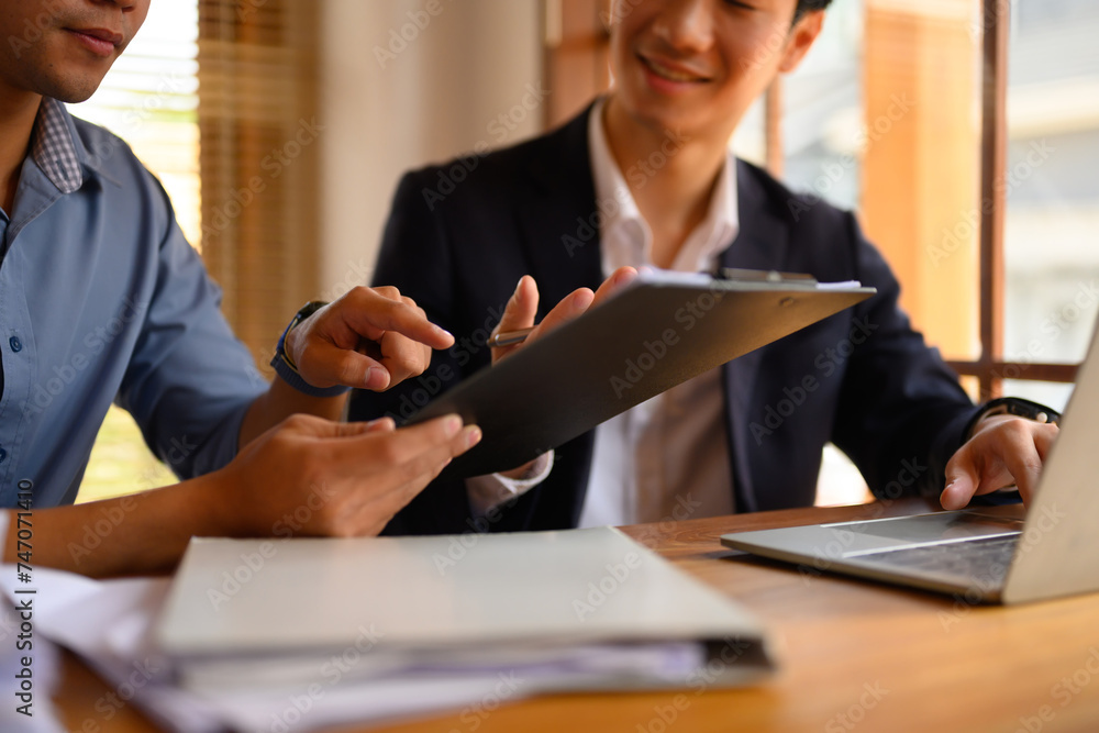 Cropped shot two financier analyzing graphs or preparing report at modern workplace Cropped shot two financier analyzing graphs or preparing report at modern workplace