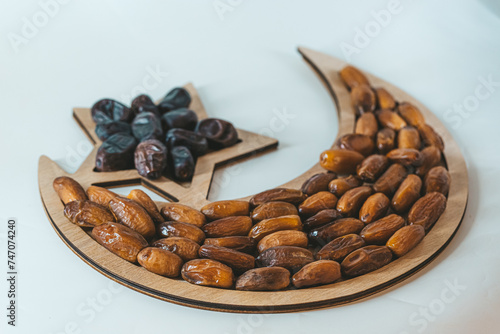 Dried dates on a wooden tray in the shape of a month and a star. Ramadan kareem background