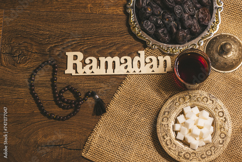 Glass of tea with sugar and dried dates on a wooden background with burlap. Ramadan Kareem holiday background. Halal meal set for fasting is obligatory for Muslim on wooden. Soft focus. Shallow DOF.