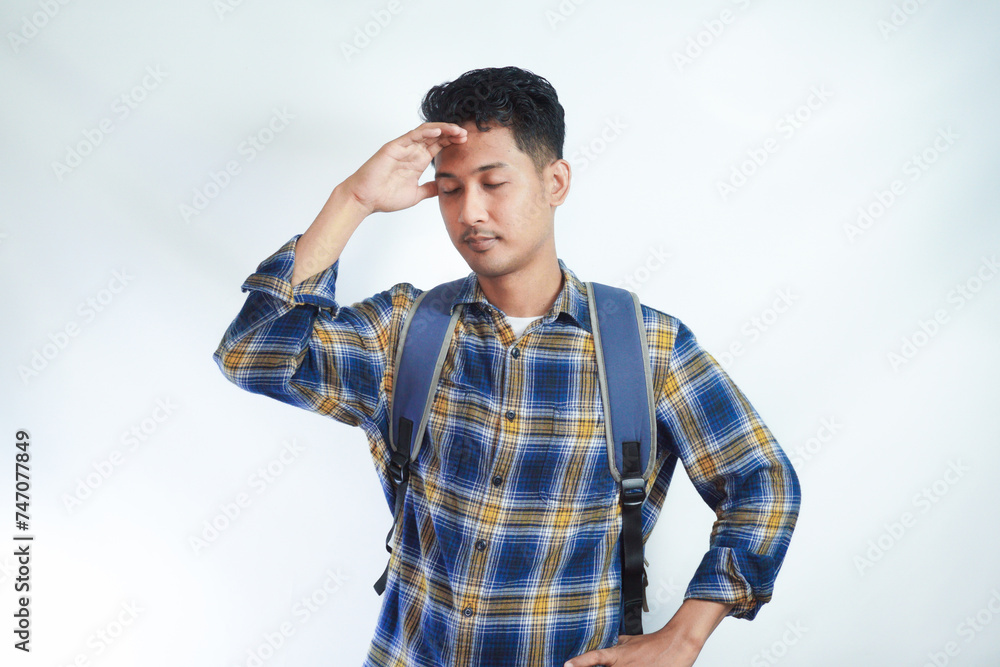 tired young Asian student man in casual clothes with backpack Keeping his eyes closed, put hand on head isolated on white background. High school university college concept tired young Asian student man in casual clothes with backpack Keeping his eyes closed, put hand on head isolated on white background. High school university college concept