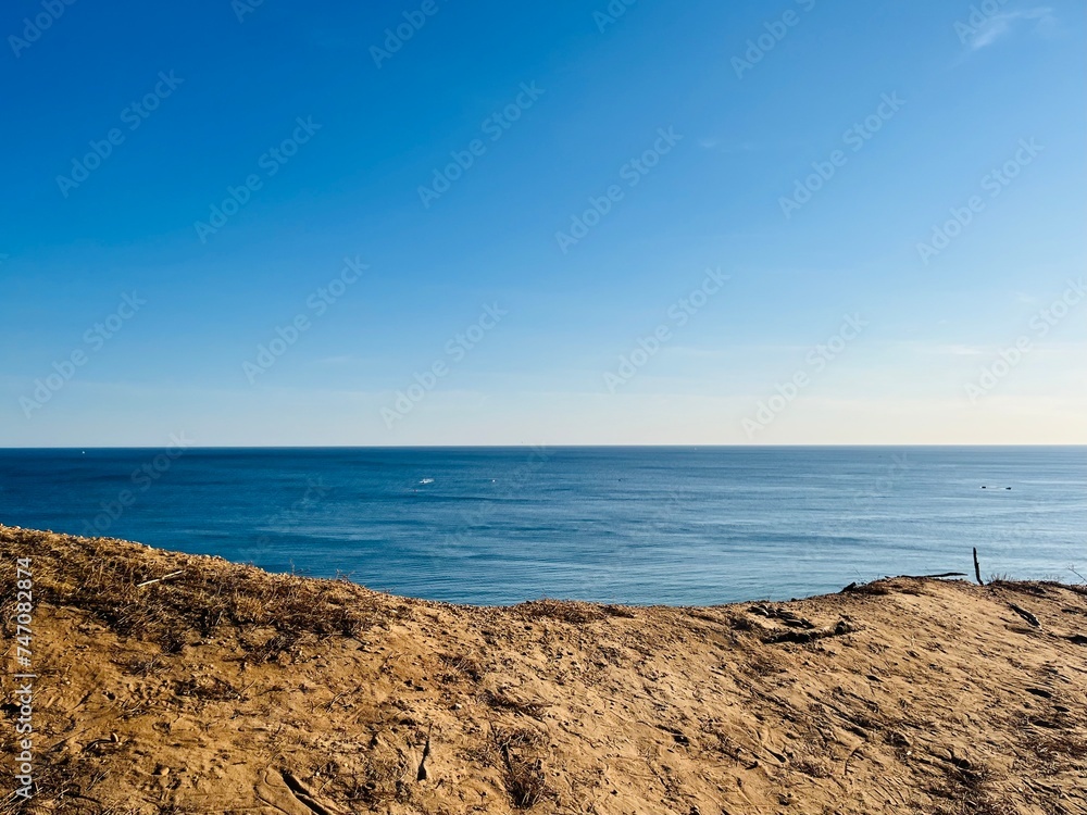 Sandstone rocky coast, blue ocean horizon, clear sky, ocean bay