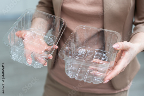 Woman hands holding empty plastic disposable food container mock up with copy space on background. Delivery food concept. 