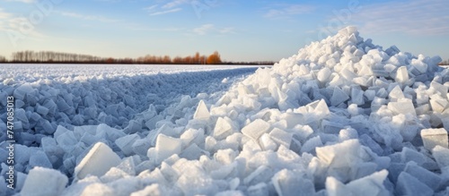 A large pile of ice is sitting in the middle of a field, creating a stunning display of salt crystals against the backdrop of a farmers field. The ice pile stands out prominently, contrasting with the