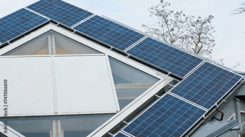 Fototapeta premium Rooftop solar panels on home in Germany. Unusual shape of the roof. Green renewable energy theme. Aerial.