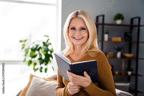 Photo of cheerful charming lady spending free time at home reading story novel indoors