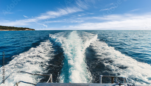 Close-up of the water wake of a speedboat or ship, view from the stern of the boat, sea view with blue sky and clouds on the horizon. Generative Ai. photo